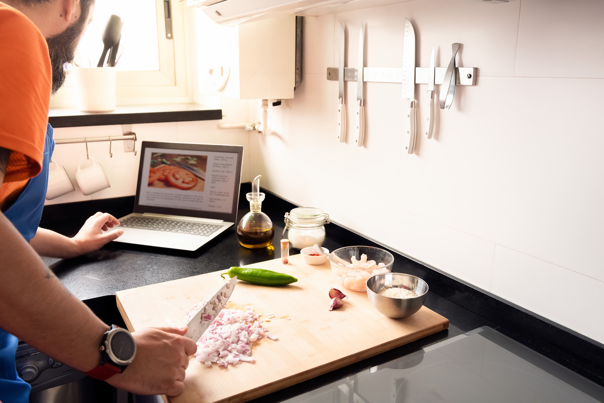 Modern kitchen workspace with cooking tools and laptop for online learning